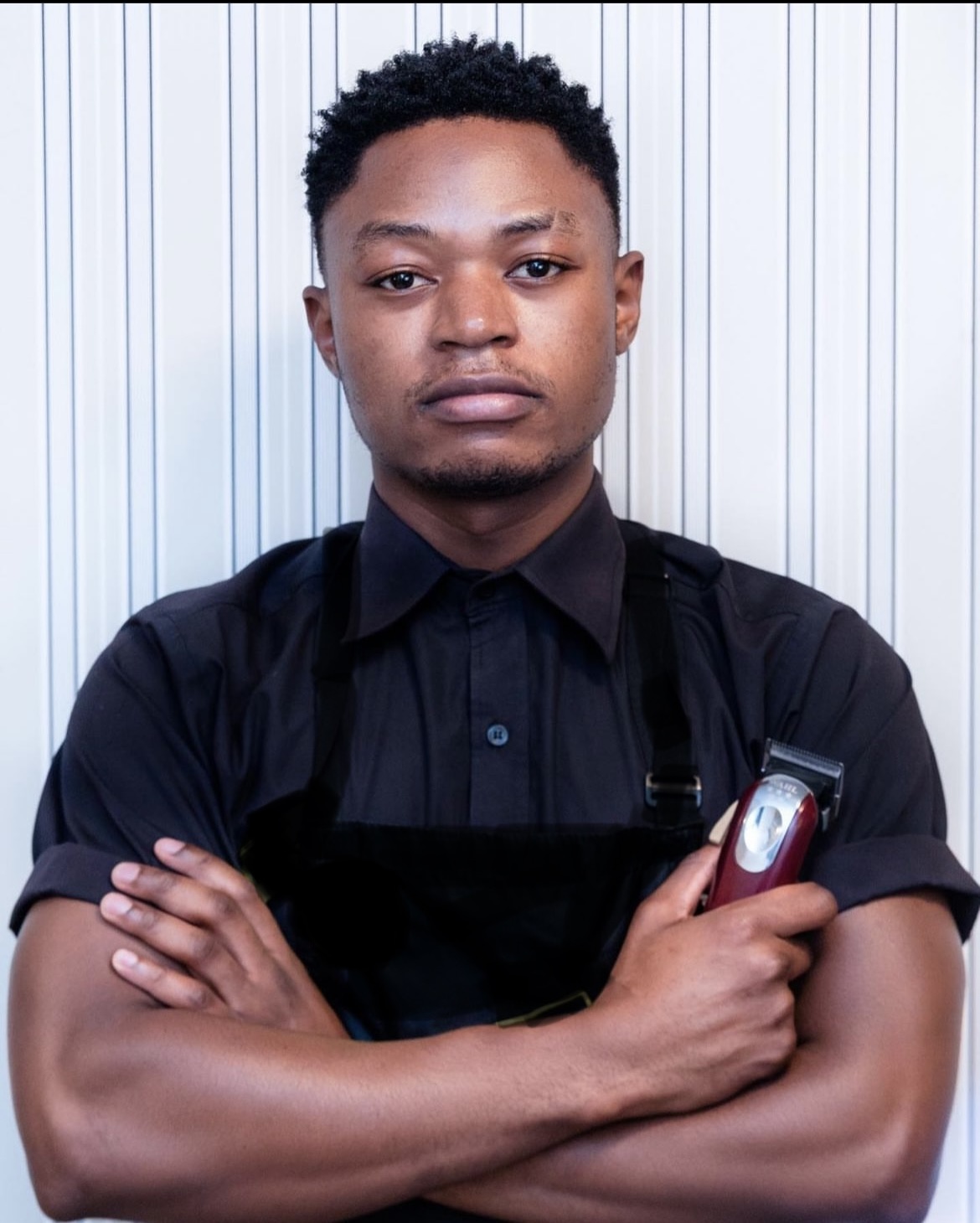 Moses, certified barber, holding his clippers